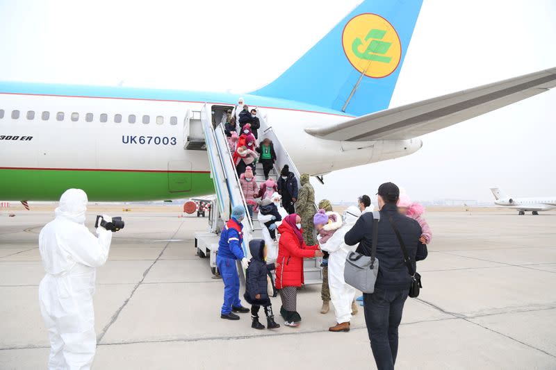 People disembark from a plane upon their arrival from Syria at an airport in Tashkent