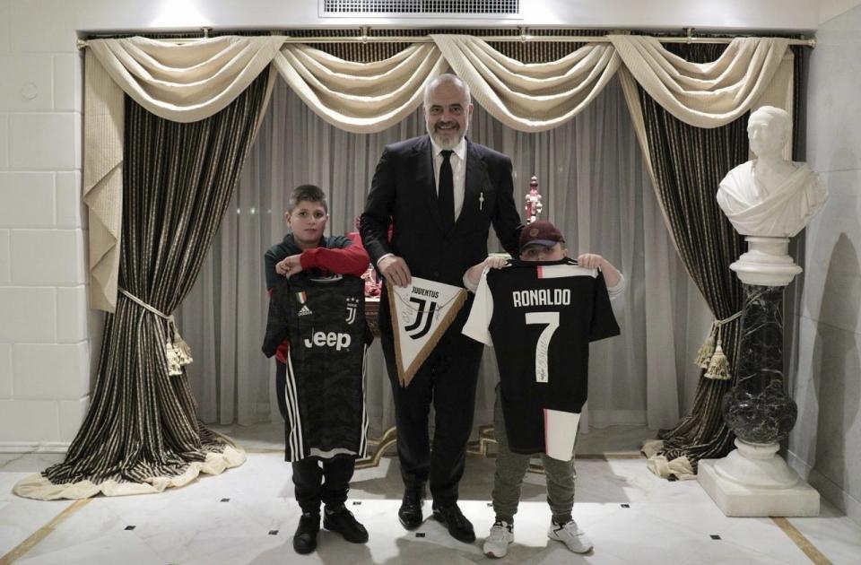 Albanian Prime Minister Edi Rama, center, poses with Aurel Lala and Alesio Cakoni, in Rome on Friday, Dec. 6, 2019. The two Albanian children were injured when they escaped their collapsing flat jolted from the Nov. 26 6.4-magnitude earthquake, that killed 51 persons and injured more than 3,000 others. They lost each two family members but their dream came true when Rama took them to Rome, Italy to meet with their sport idols Ronaldo and Buffon. (Albanian Prime Minister Office via AP)