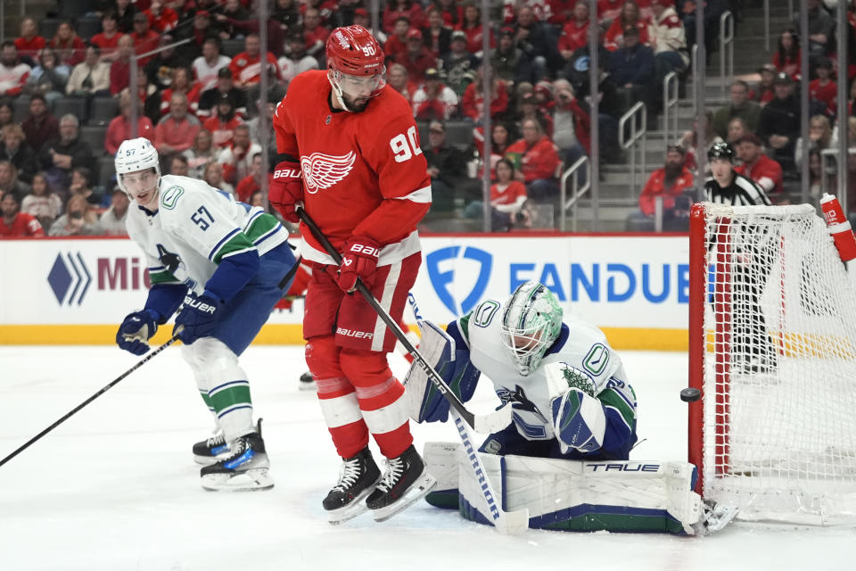 Detroit Red Wings center Joe Veleno (90) tries to screen Vancouver Canucks goaltender Casey DeSmith (29) on a shot as Tyler Myers (57) defends in the first period of an NHL hockey game Saturday, Feb. 10, 2024, in Detroit. (AP Photo/Paul Sancya)