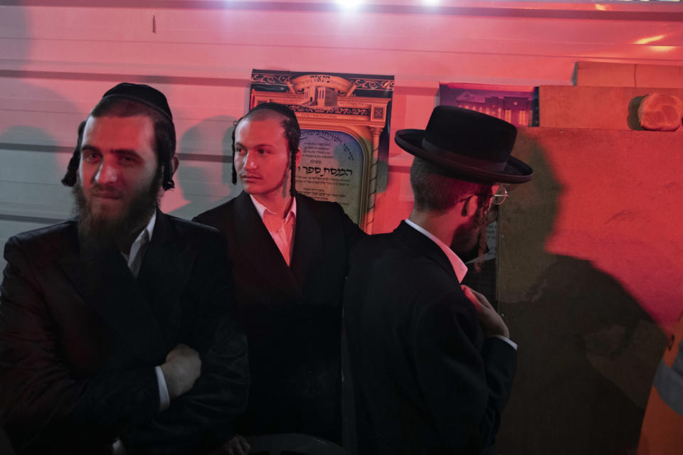 Ultra-Orthodox Jewish youths stand outside a synagogue in Givat Zeev, outside Jerusalem, Sunday, May 16, 2021. Israeli medics say more than 150 people were injured in a fatal collapse of a bleacher at an uncompleted West Bank synagogue. (AP Photo/Sebastian Scheiner)