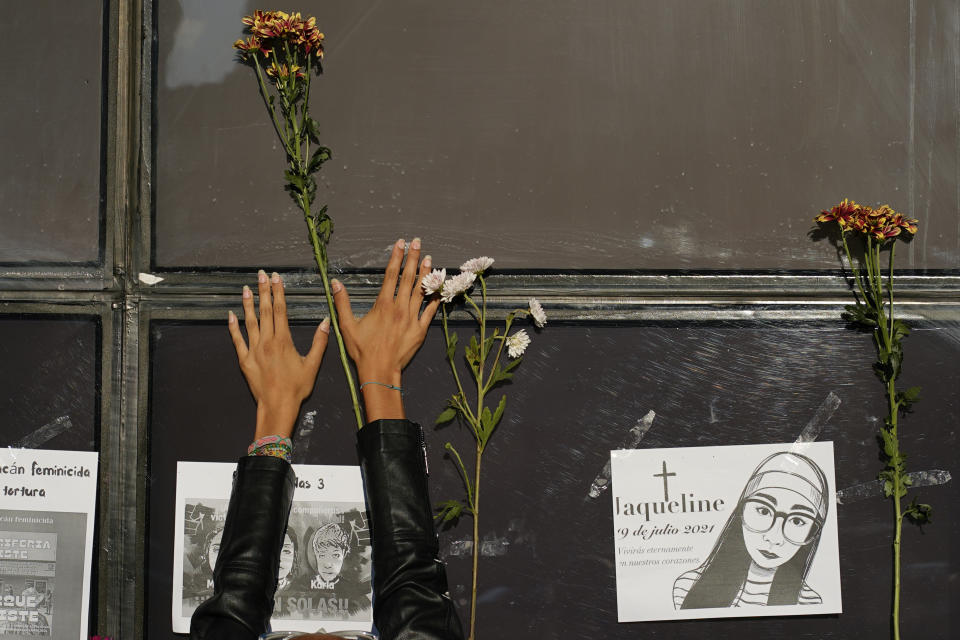 A woman places a stem of flowers on the facade of the Attorney General's office during a protest against the disappearance of Debanhi Escobar and other women who have gone missing, in Mexico City, Friday, April 22, 2022. The protest against femicide was triggered after Escobar's decomposing body was recently found in a subterranean water tank at a motel when workers reported foul odors coming from the water holding tank. (AP Photo/Eduardo Verdugo)