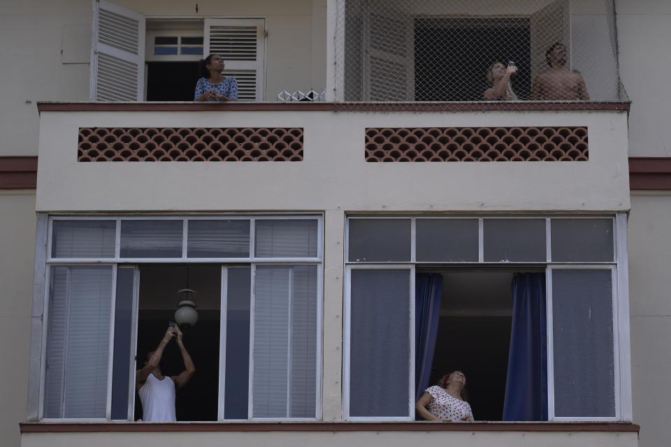 People watch firefighter Elielson Silva play his trumpet from the top of a ladder for residents during a lockdown to help contain the spread of the new coronavirus in Rio de Janeiro, Brazil, Sunday, April 5, 2020. Silva raised his silver trumpet to his lips and the notes soared toward his audience, helping extinguish the blues from being cooped up inside their homes. (AP Photo/Leo Correa)