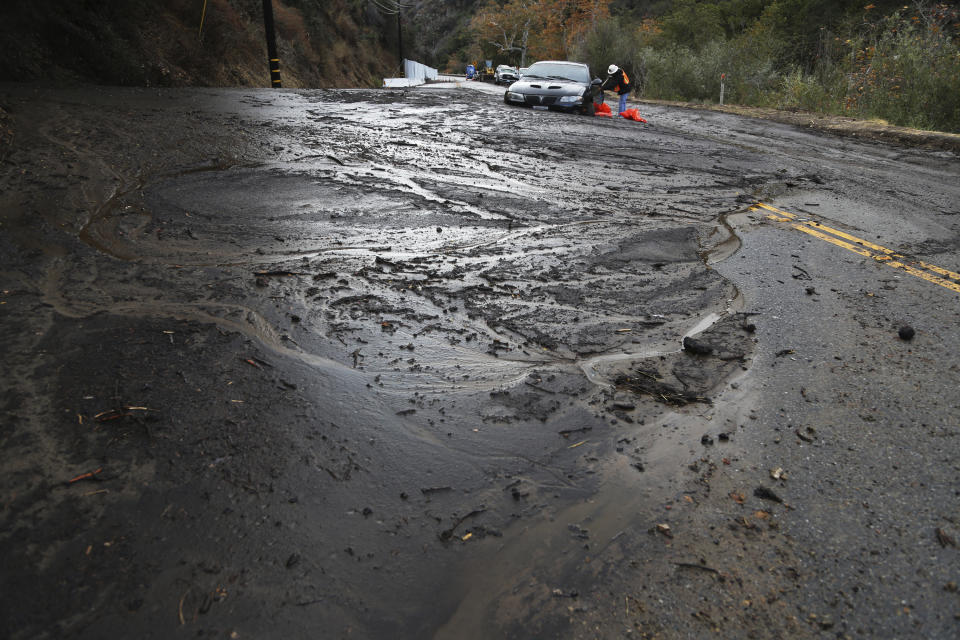 <p>A worker tries to free a car is trapped in a deep debris flow that covered parts of Topanga Canyon Boulevard near the village of Topanga west of Los Angeles, Tuesday, Jan. 9, 2017. (Photo: Reed Saxon/AP) </p>