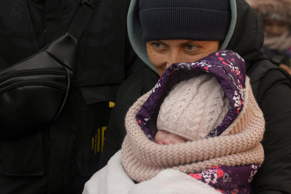 A refugee fleeing the conflict from neighbouring Ukraine holds a child inside a tent at the Romanian-Ukrainian border, in Siret, Romania, Saturday, March 5, 2022. (AP Photo/Andreea Alexandru)