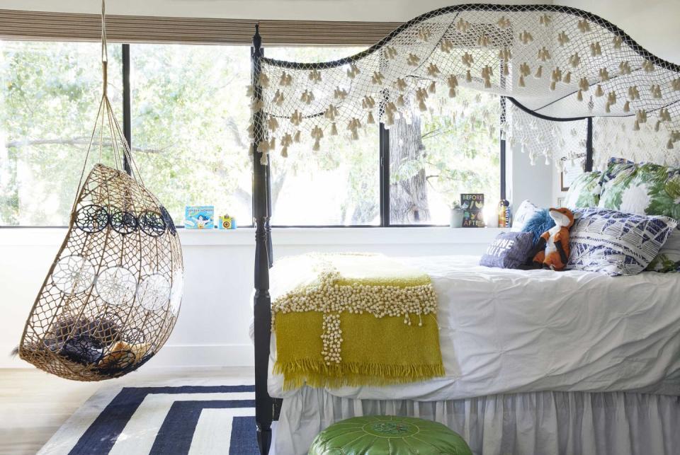 a bohemian style bedroom with a hanging egg chair and a canopy bed