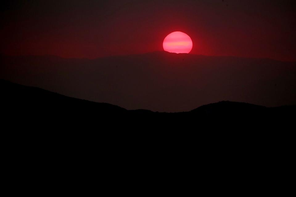 The sun sets behind a pall of smoke from the Fairview fire