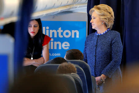 U.S. Democratic presidential nominee Hillary Clinton talks to staff members, including aide Huma Abedin (L), onboard her campaign plane in White Plains, New York, U.S. October 28, 2016. REUTERS/Brian Snyder