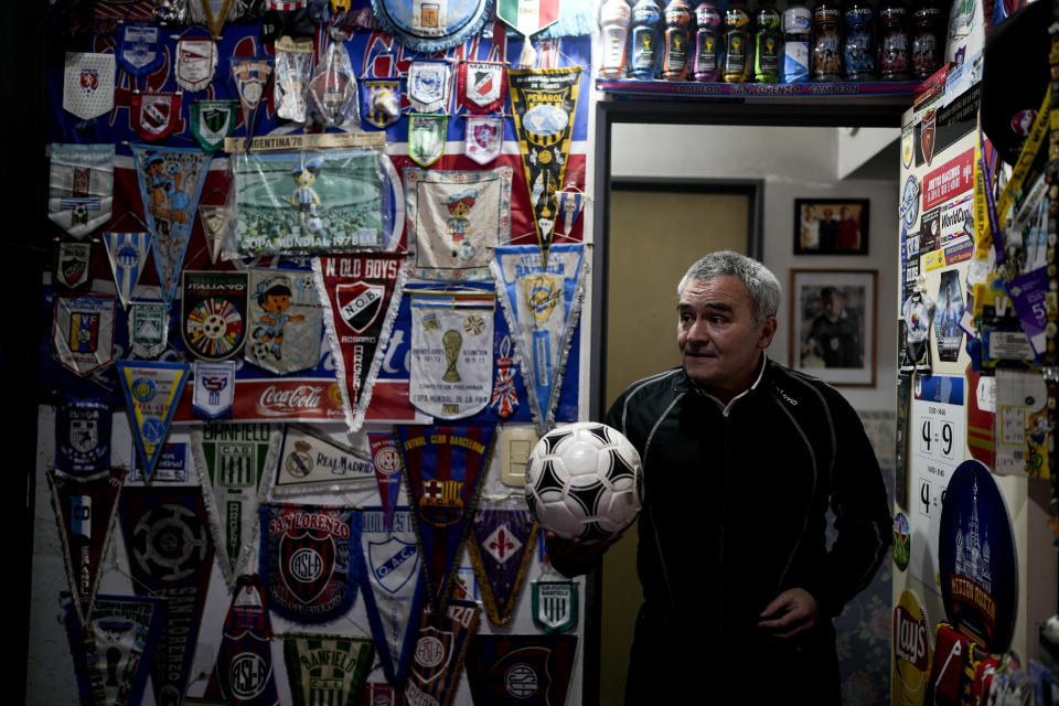 Osvaldo Santander holds a soccer ball in a room at his home during an interview with The Associated Press, in Buenos Aires, Argentina, Thursday, Aug. 18, 2022. Santander and his son Julian will travel to Qatar for the World Cup, their third World Cup as fans. (AP Photo/Natacha Pisarenko)