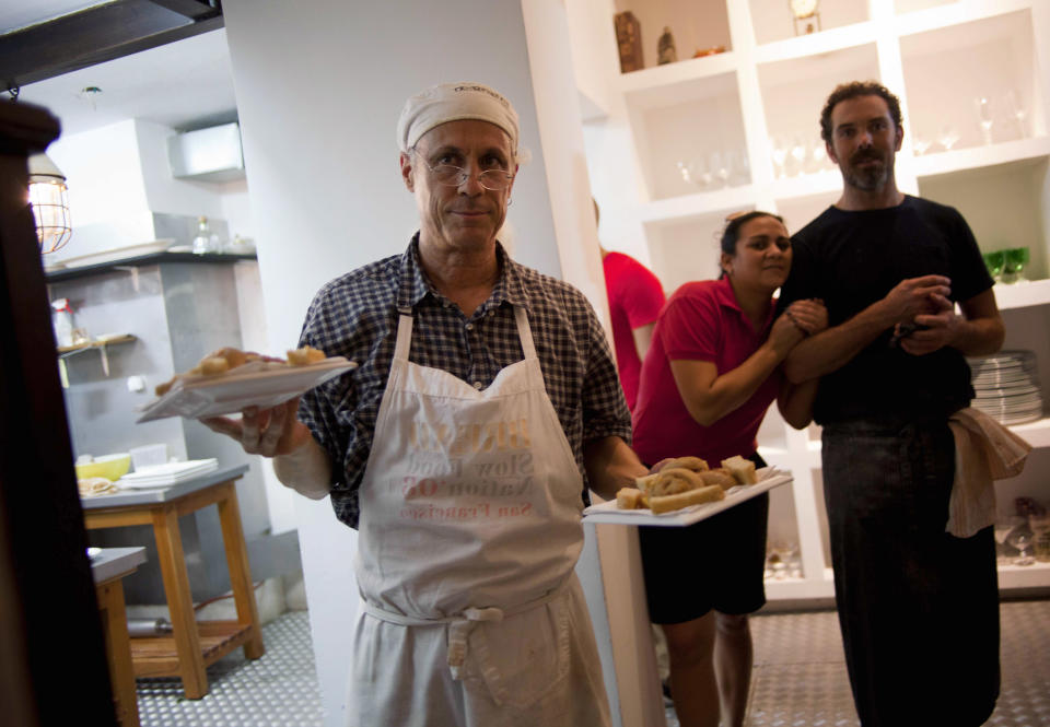 In this Dec. 7, 2012 photo, U.S. chef Steve Sullivan holds plates of bread as fellow chef Charlie Hallowell, right, looks toward the dining room of the privately-run restaurant Le Chansonnier in Havana, Cuba. Sullivan and Hallowell visited Cuba as part of the "Planting Seeds" delegation that held give-and-take seminars with chefs and culinary students about slow food. They also put on two dinners including a rabbit-based meal at the privately run Le Chansonnier. (AP Photo/Ramon Espinosa)