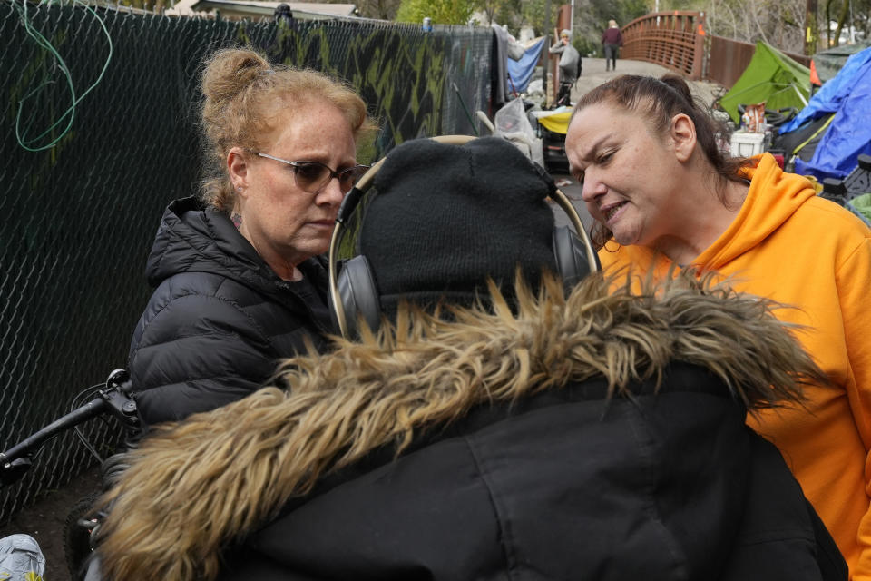 Members of the Resiliency Empowerment Support Team (REST), Beth Perkins, left, and Letha Croff, right, talk with a homeless person during a visit to a homeless camp in Chico, Calif., Feb. 8, 2024. A measure aimed at transforming how California spends money on mental health will go before voters in March as the state continues to grapple an unabated homelessness crisis. The REST Program does daily visits to homeless encampments to get them into treatment or housing. Butte County officials fear the REST program would lose its funding if California voters approve Proposition 1. (AP Photo/Rich Pedroncelli)