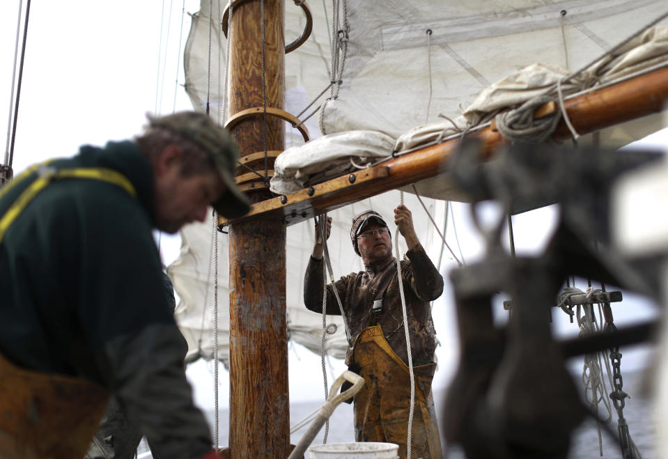 In this Dec. 20, 2013 picture, Ted Williams Daniels, back center, adjusts the mainsail on the skipjack Hilda M. Willing in Tangier Sound near Deal Island, Md. (AP Photo/Patrick Semansky)