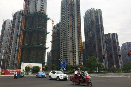 People drive past residential buildings under construction in Bengbu, Anhui province, China July 8, 2017. Picture taken July 8, 2017. REUTERS/Yawen Chen