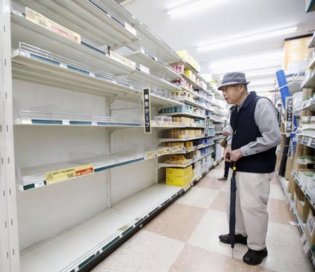 A man stands in front of empty shelves in a shop in Yokohama