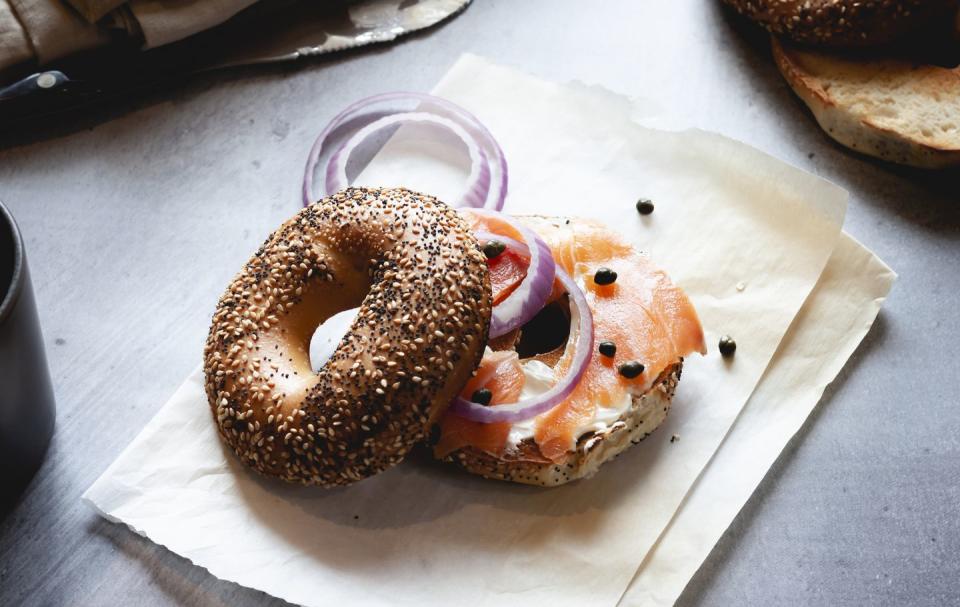 closeup of lox bagel with onions on paper sheet