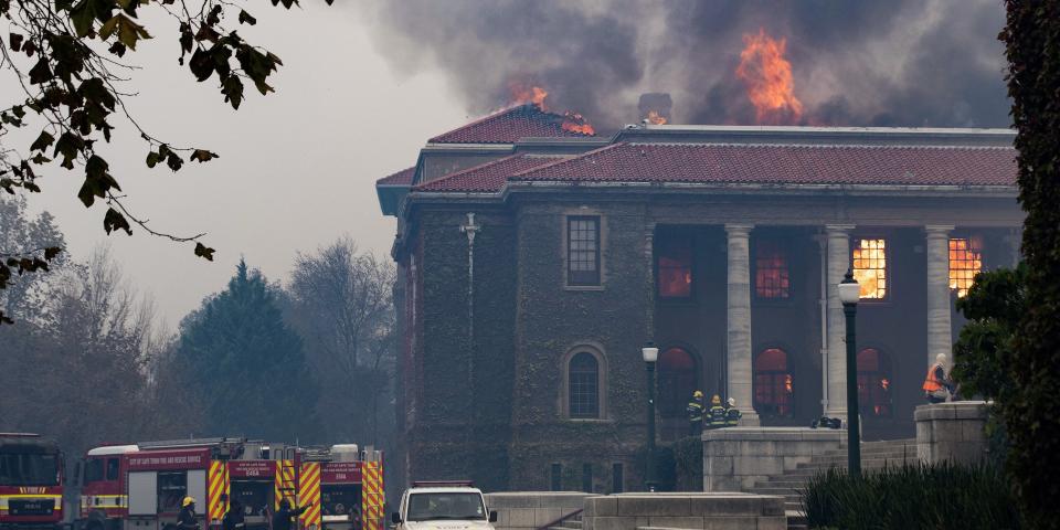 TOPSHOT - Firefighters try, in vain, to extinguish a fire in the Jagger Library, at the University of Cape Town, after a forest fire came down the foothills of Table Mountain, setting university buildings alight in Cape Town, on April 18, 2021. (Photo by RODGER BOSCH / AFP) (Photo by RODGER BOSCH/AFP via Getty Images)