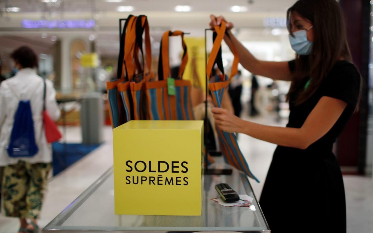 An employee, wearing a protective face mask, checks bags with discount signs at the department store Le Printemps Haussmann in Paris -  GONZALO FUENTES/Reuters