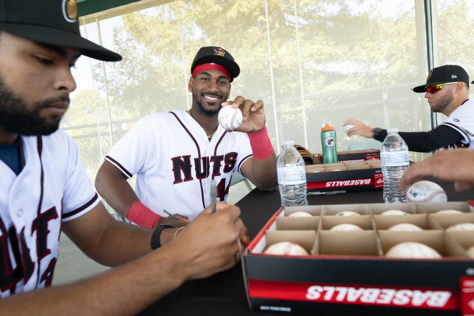 Modesto Nuts players Pedro Da Costa Lemos, left, and Lazaro Montes, middle, sign baseballs with teammates during media day at John Thurman Field in Modesto, Calif., Tuesday, April 2, 2024.