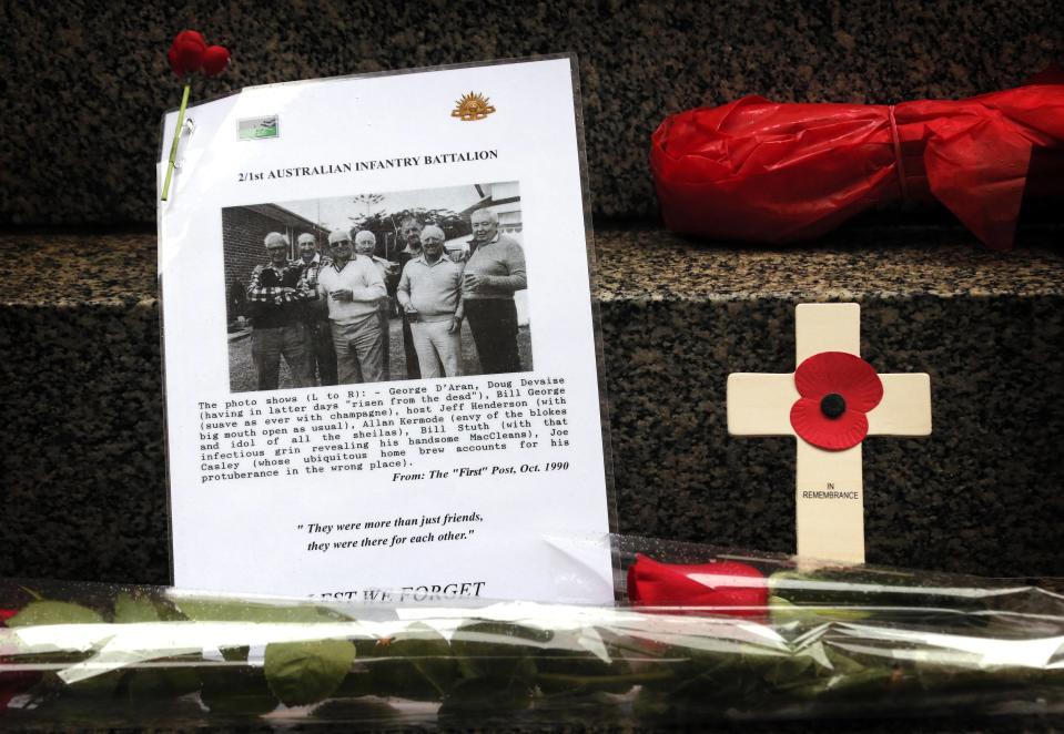 A tribute to war veterans can be seen next to flowers and wreaths laid at the base of the Cenotaph during a Remembrance Day ceremony in Sydney