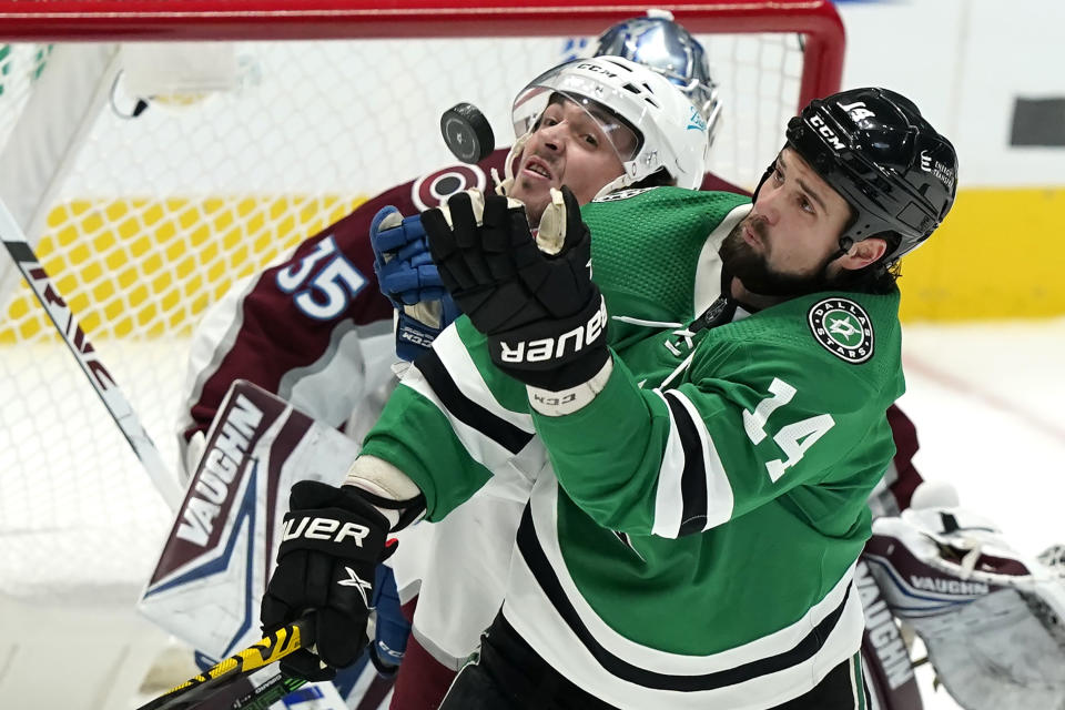 Dallas Stars left wing Jamie Benn (14) reaches for the puck in front of Colorado Avalanche defenseman Samuel Girard during the first period of an NHL hockey game in Dallas, Friday, Nov. 26, 2021. (AP Photo/LM Otero)