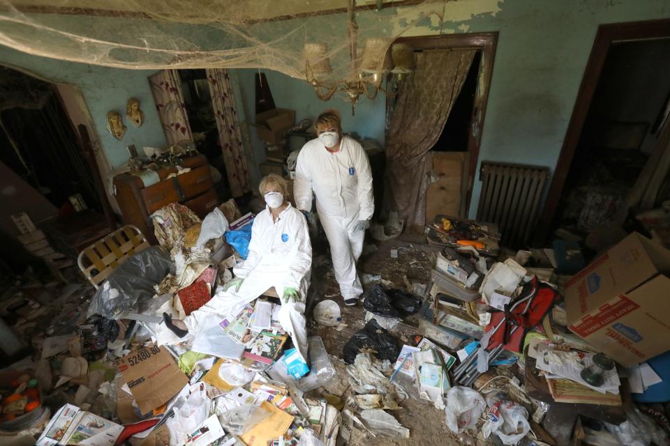 Linda Kajma (sitting) and friend and colleague Tamara Tracy inside the family room of Sally and Lorraine Honeycheck during a cleaning of the house on Sunday, June 23, 2019. The house was full of many items like old newspapers, torn mattresses covered in rat droppings, stacked up dishes and uneaten food is making it hard to Kajma to dig through and find valuable possessions, insurance forms, money and other important items left behind when Sally died.