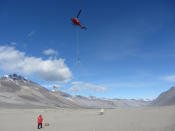 A helicopter begins a survey with an airborne electromagnetic mapping sensor at Bull Pass in the Wright Valley, McMurdo Dry Valleys, Antarctica.
