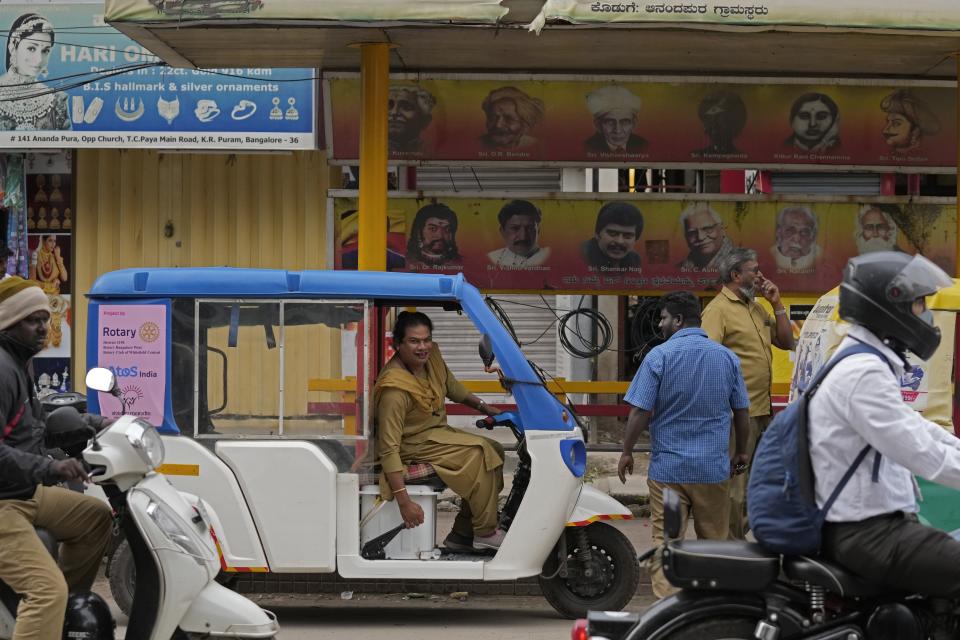 Preethi, a 38-year-old transgender woman who uses only her first name, parks her electric auto rickshaw next to a bus stop to look for passengers in Bengaluru, India, Wednesday, July 12, 2023. Electric vehicles sales are skyrocketing, and experts say it’s crucial that everyone benefits from these big moves toward clean energy. (AP Photo/Aijaz Rahi)