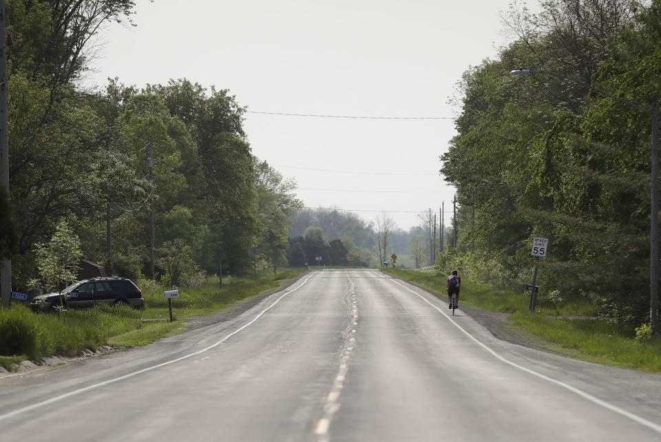 A person bikes May 23 along the side of County II in Zittau. The county highway is the main artery through the unincorporated community.