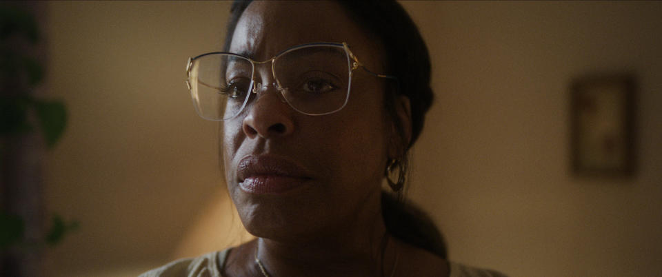 closeup of her in character wearing no makeup and large framed glasses