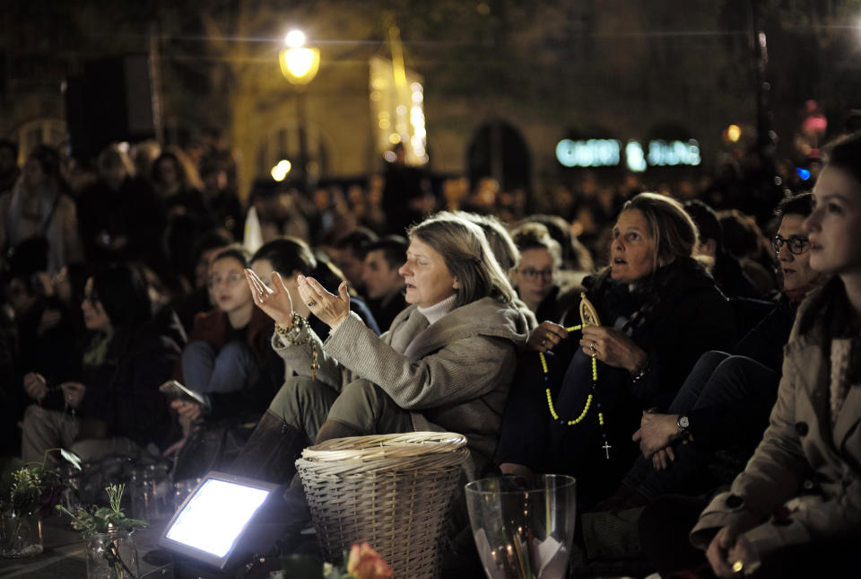 People attend a vigil in Paris, Tuesday April 16, 2019. Firefighters declared success Tuesday in a more than 12-hour battle to extinguish an inferno engulfing Paris' iconic Notre Dame cathedral that claimed its spire and roof, but spared its bell towers and the purported Crown of Christ. (AP Photo/Kamil Zihnioglu)