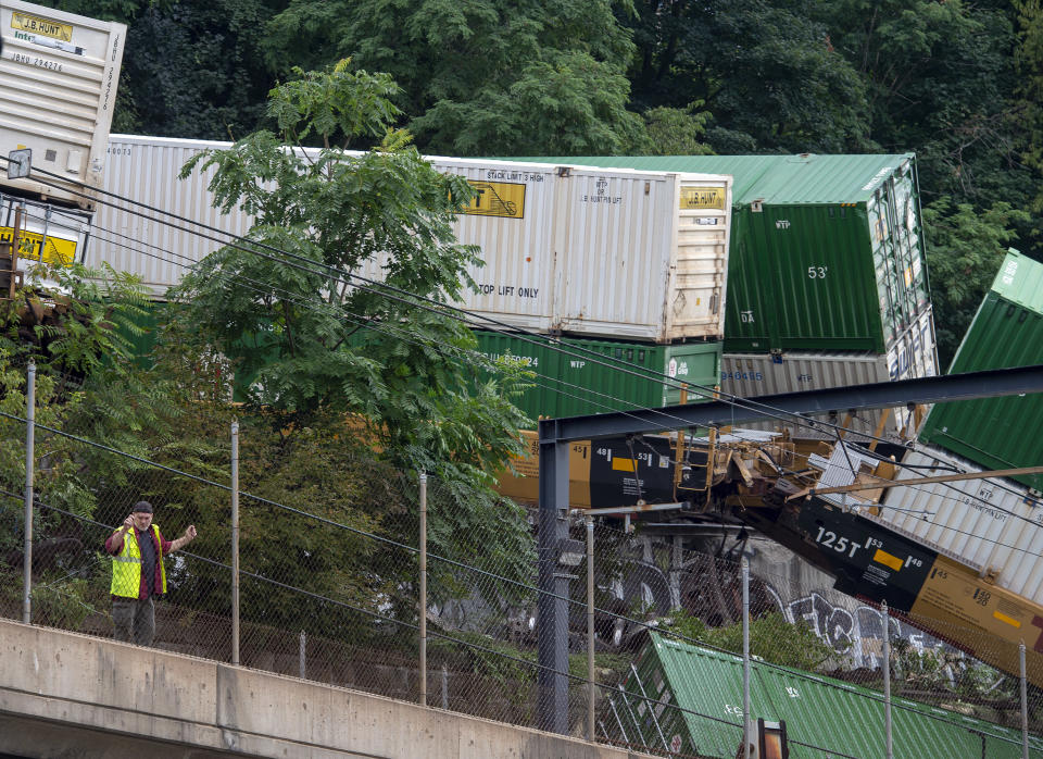 Emergency personnel work the scene of a train derailment above Carson Street on Sunday, Aug. 5, 2018, near Station Square in Pittsburgh. Four cars from a freight train derailed in Pittsburgh, sending containers tumbling down a hillside onto light rail tracks below, but no injuries have been reported, authorities said. (Steph Chambers/Pittsburgh Post-Gazette via AP)