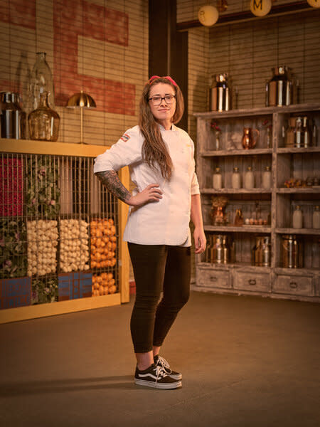 Full lengths of Alisha Elenz in her chef's uniform in a kitchen pantry.