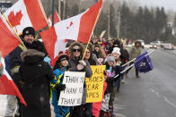 Protesters and supporters against a COVID-19 vaccine mandate for cross-border truckers cheer as a parade of trucks and vehicles pass through Kakabeka Falls outside of Thunder Bay, Ontario, on Wednesday, Jan. 26, 2022. (David Jackson/The Canadian Press via AP)