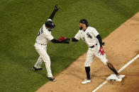 Chicago White Sox's Billy Hamilton, right, celebrates his RBI triple off Minnesota Twins starting pitcher J.A. Happ with third base coach Joe McEwing during the first inning of a baseball game Wednesday, May 12, 2021, in Chicago. (AP Photo/Charles Rex Arbogast)