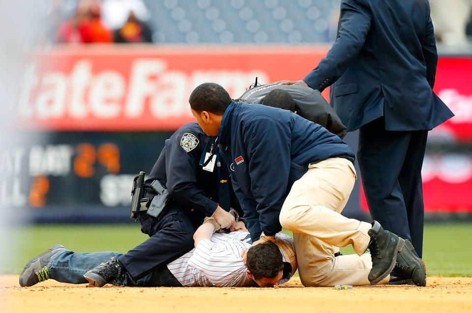 Police and security subdue a fan who ran onto the field during the eighth inning of a game between the New York Yankees and the Baltimore Orioles at Yankee Stadium on April 8, 2014 in the Bronx borough of New York City. (Photo by Jim McIsaac/Getty Images)