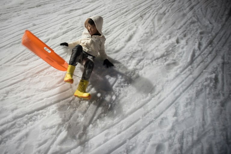 A boy laughes after he crashes while sledding at Snow Town in Bangkok