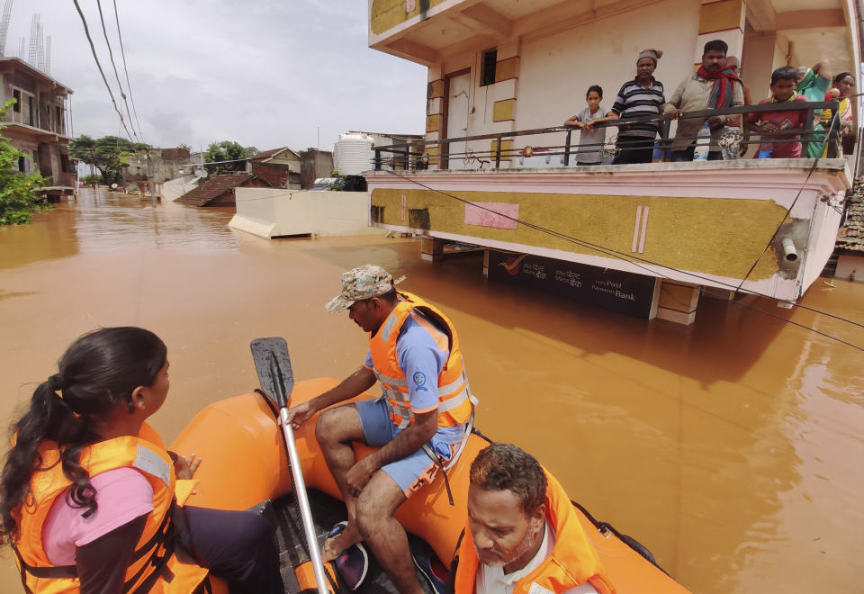 People stranded in flood waters watch others being rescued at Kolhapur in western Maharashtra state, India, Saturday, July 24, 2021. Officials say landslides and flooding triggered by heavy monsoon rain have killed more than 100 people in western India. More than 1,000 people trapped by floodwaters have been rescued. (AP Photo)