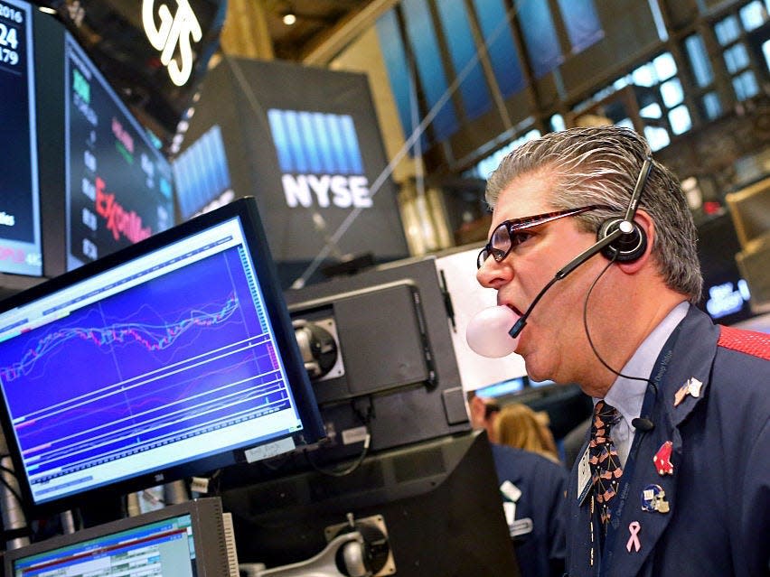 A trader blows out a chewing gum bubble while working on the floor of the New York Stock Exchange