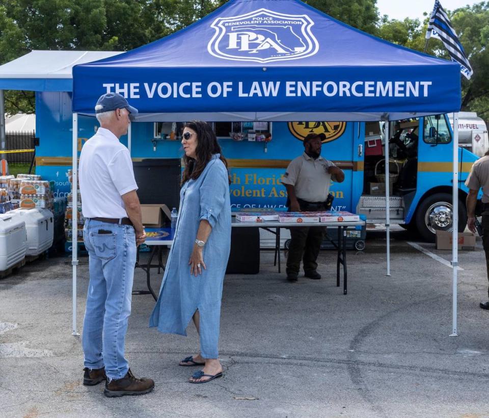 Surfside Mayor Charles Burkett, left, speaks to volunteer Kelly Gold, at a station set up by the Police Benevolent Association near the scene of the Champlain Towers South collapse on July 15, 2021.