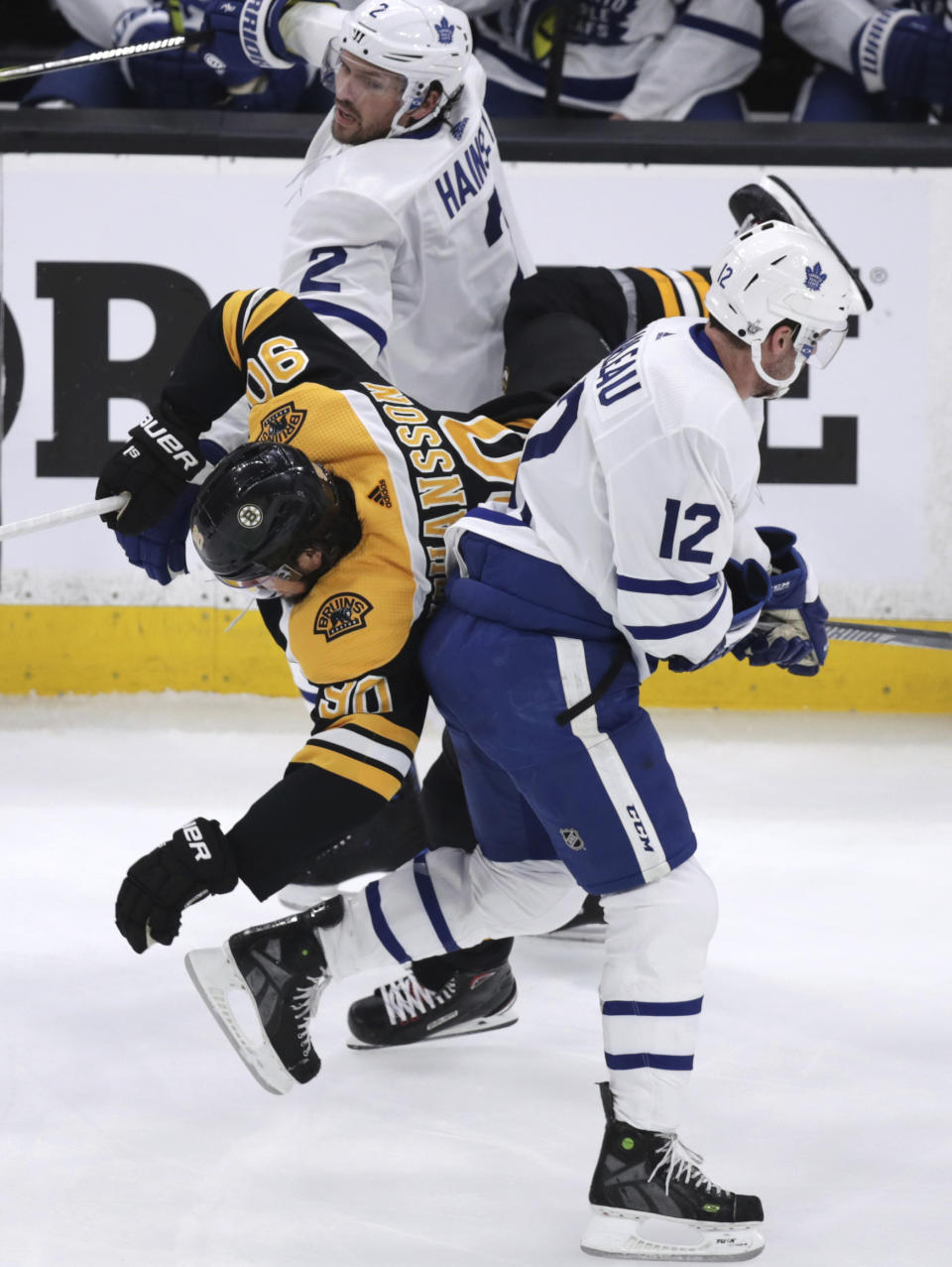 Boston Bruins left wing Marcus Johansson (90) goes airborne as he is sandwiched between Toronto Maple Leafs center Patrick Marleau (12) and defenseman Ron Hainsey (2) during the first period of Game 7 of an NHL hockey first-round playoff series, Tuesday, April 23, 2019, in Boston. (AP Photo/Charles Krupa)