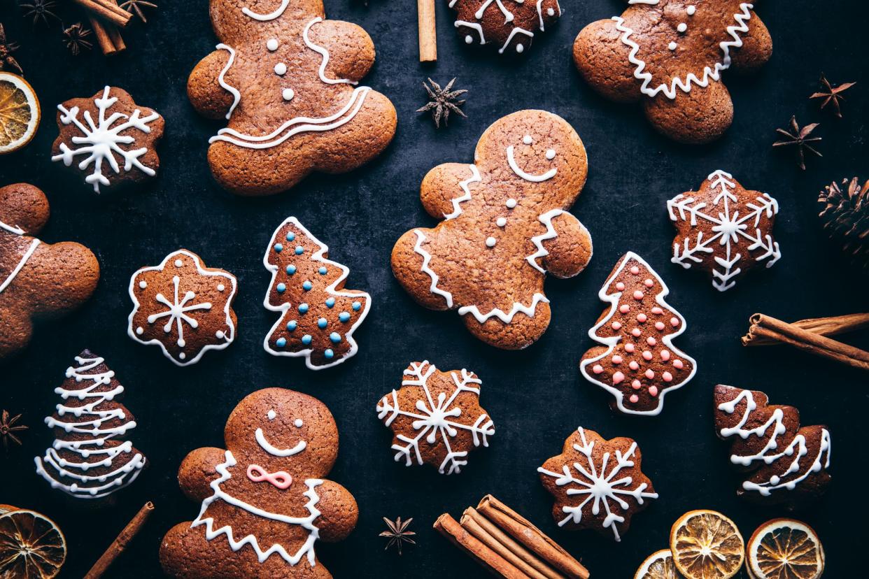 Directly above shot of decorated gingerbread cookies with spices on table. Homemade Christmas cookies on gray background.