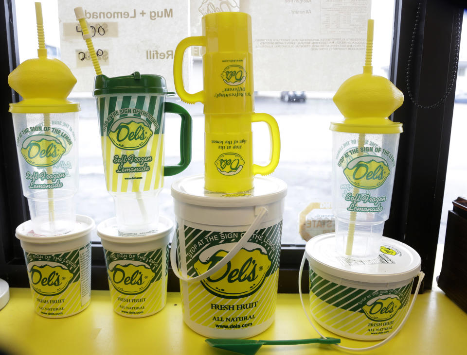 This April 30, 2014 photo shows drink containers in the window of a Del's Lemonade location in Cranston, R.I. The lemony slush, made of water, sugar, lemon juice and chunks of rind, has become a cultural icon in the state. It's not unusual to see the trucks or carts at wedding receptions, birthday parties, bar mitzvahs, and troop deployments and homecomings. (AP Photo/Steven Senne)