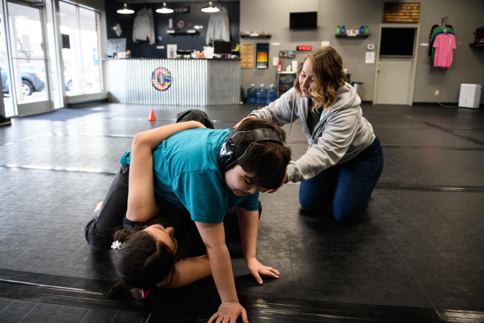 Emma Shields, right, guides Mia Martin and Bradley Harrell through a sweep during a Children's Adaptive Brazilian Jiu Jitsu class at Martial Arts of NC on Tuesday, Feb. 8, 2022.