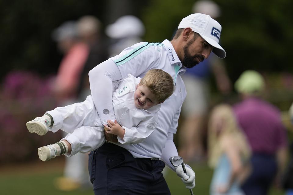 Matthieu Pavon, of France, lifts his son Aaron on the fifth green during the par-3 contest at the Masters golf tournament at Augusta National Golf Club Wednesday, April 10, 2024, in Augusta, GA. (AP Photo/George Walker IV)