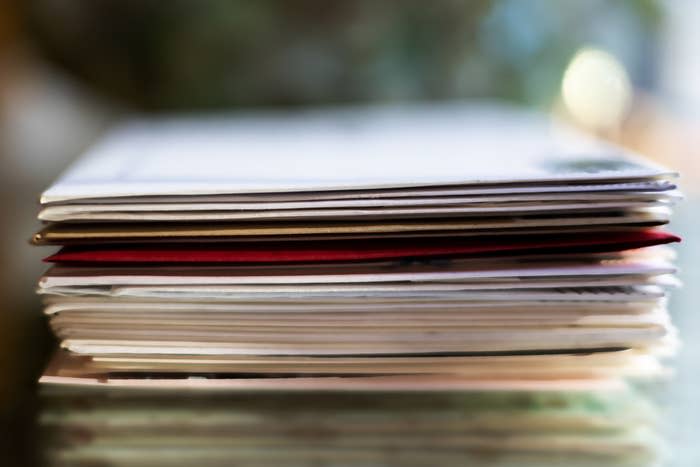 A close-up image of a stack of envelopes piled neatly, one atop another, on a flat surface