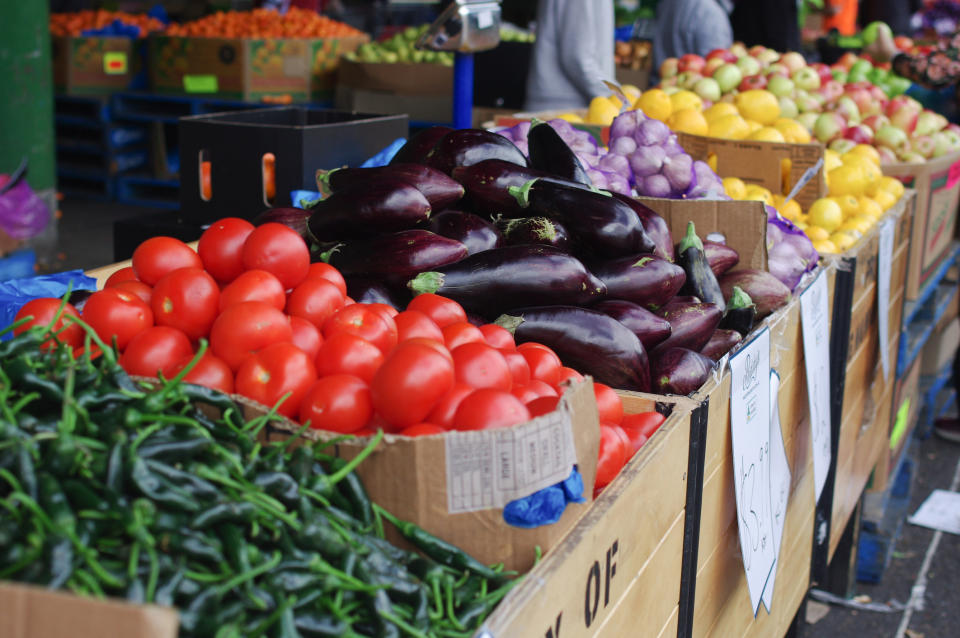 various fruits and vegetables in boxes being sold at an outdoor market