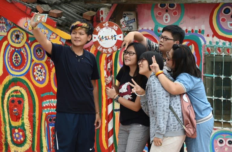 Tourists pose for selfies next to artwork by artist Huang Yung-fu, while visiting the Rainbow Village in Taichung, central Taiwan