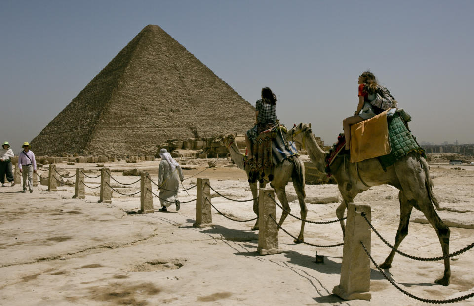 Varios turistas montan camellos durante una visita a las Pirámides de Giza, cerca de El Cairo, Egipto, el martes 21 de mayo de 2019, dos días después de que un autobús turístico activó un artefacto explosivo improvisado cerca del lugar, hiriendo a más de una decena de turistas extranjeros. (Foto AP/Maya Alleruzzo)