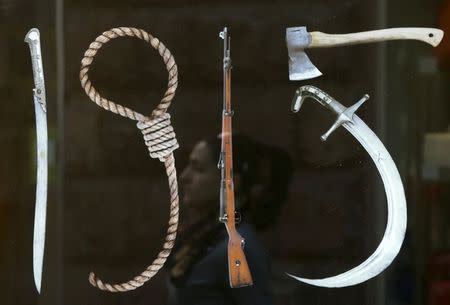 A woman is reflected in a display containing a banner depicting "Tools of Genocide" forming the shape of "1915", in reference to the year of the mass killings of Armenians by Ottoman Turks, in Yerevan, April 22, 2015. REUTERS/David Mdzinarishvili