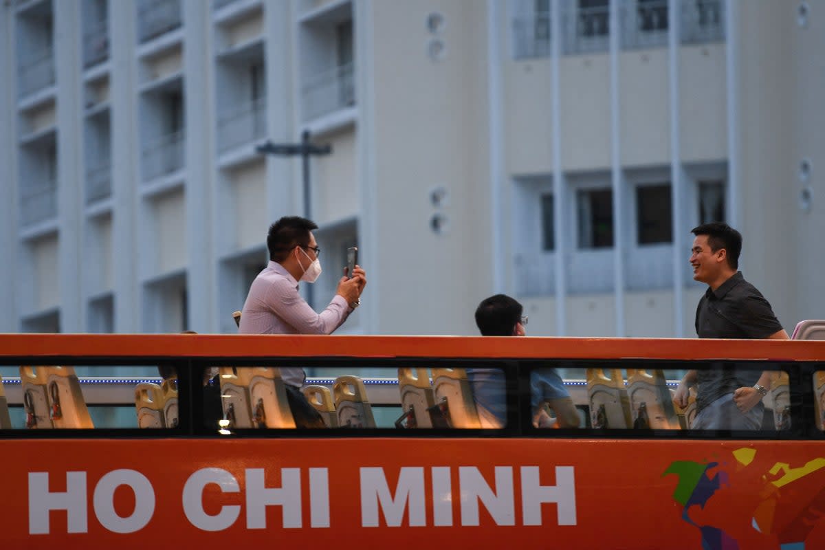 Representative: A tourist takes a photo with his mobile phone as people tour Ho Chi Minh City in a sightseeing bus on 1 December 2021 (AFP via Getty Images)