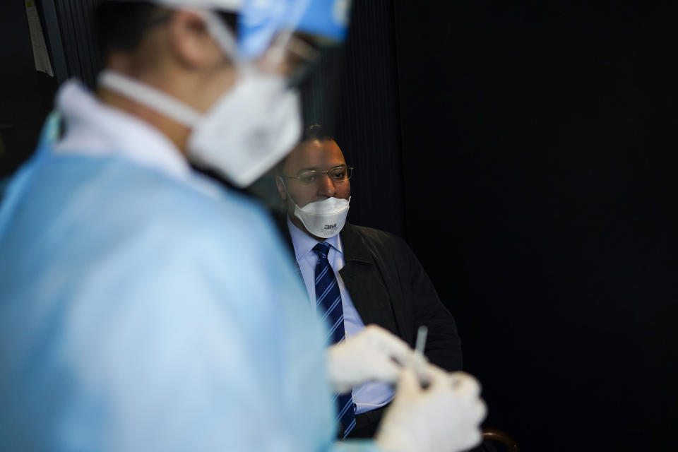 A medical worker, wearing a full protective gear, takes a nose swab from a traveller who arrived from U.K., to be tested for COVID-19 in a Red Cross test center at Gare du Midi international train station in Brussels, Tuesday, Jan. 19, 2021. Belgium is strengthening its rules for travellers entering the country by train or bus in a bid to limit the spread of a more contagious variant of the coronavirus detected in Britain. (AP Photo/Francisco Seco)